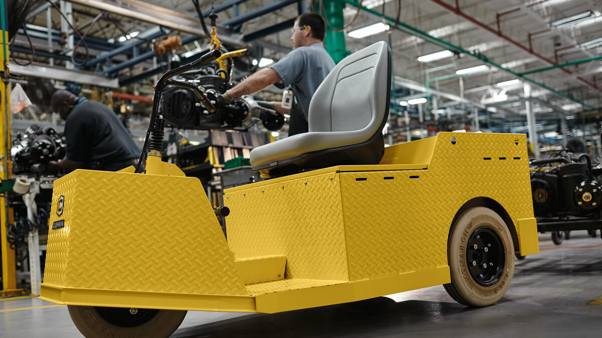 A hand plugs a charger into an E-Z-GO vehicle